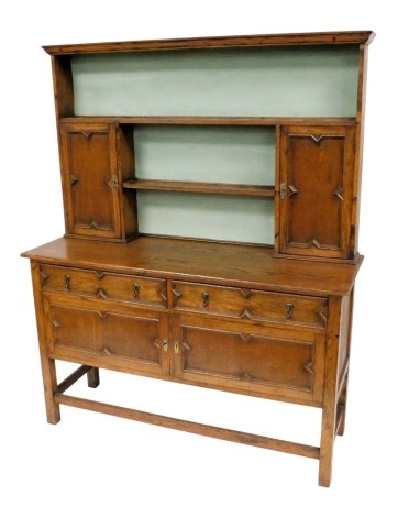 A Victorian oak dresser, the outswept pediment above a plate rack of one long and one short shelf, flanked by a pair of cupboard doors, over two frieze drawers above further cupboard doors, raised on stiles united by a box stretcher, 168.5cm high, 138cm w