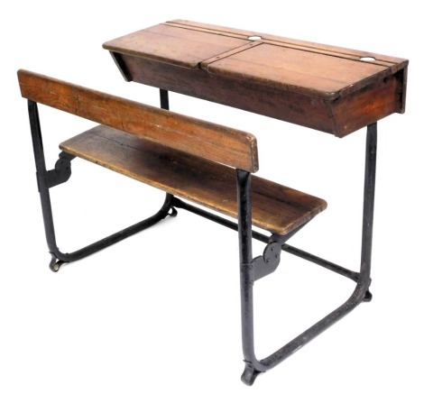 A Victorian child's oak double school desk, with bench, raised on a cast iron frame, 78cm high, 103cm wide, 72cm deep.