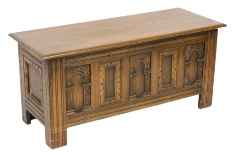 An Old Charm style oak coffer, with a panelled front, raised on stiles, 53cm high, 114cm wide, 46cm deep.