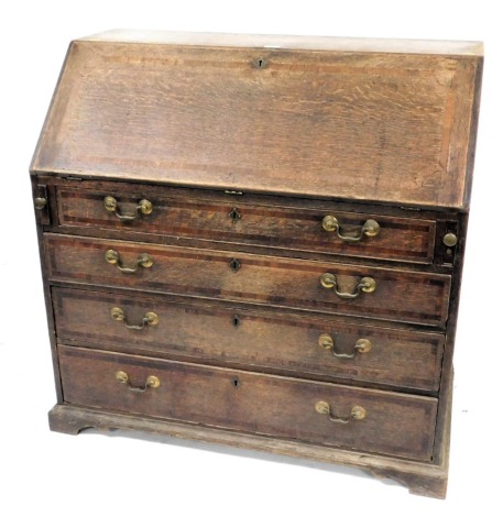 A George III oak bureau, mahogany banded top, the fall flap resting on lopers, and revealing an extensively fitted interior of drawers, pigeon holes, secret compartments, and central cupboard, over four graduated drawers with mahogany banding and brass sw