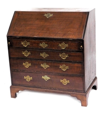 A George III oak bureau, the fall flap opening to reveal a central door and drawer, flanked by eight recesses and further drawers, above four long graduated drawers, raised on bracket feet, 102cm high, 92cm high, 52cm wide.