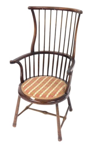 A West Country style stick back high back Windsor style chair, with a shaped cresting rail and scroll arm, with overstuffed petit point embroidery on tapering front legs, joined by a H stretcher, 110cm high.