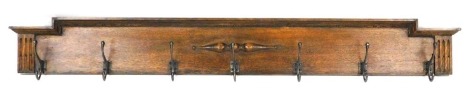 A late Victorian oak hanging coat rack, with seven scrolling metal hooks, 149cm wide.