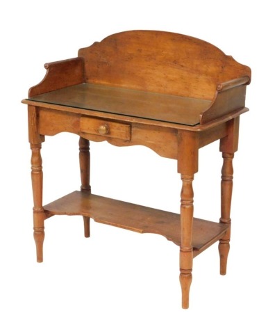 A Victorian pine washstand, the top with a glass protector, over a small frieze drawer, raised on turned legs untied by a shaped undertier, 105cm high, 90cm wide, 45.5cm deep.