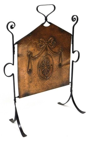 A late Victorian cast iron and copper firescreen, embossed in the Adam style with an oval medallion and tied bow, raised on a scrolling cast iron frame, 77cm high, 59cm wide.