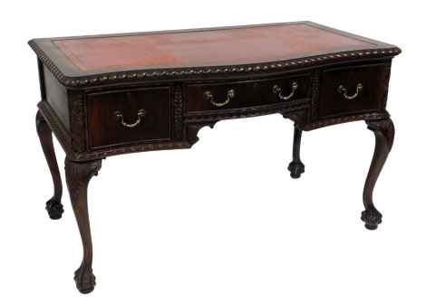 A Georgian style mahogany serpentine desk, with a gilt red tooled red leather top, above one long and two deep drawers, raised on leaf carved cabriole legs and ball and claw feet, 78cm high, 129cm wide, 71cm deep.