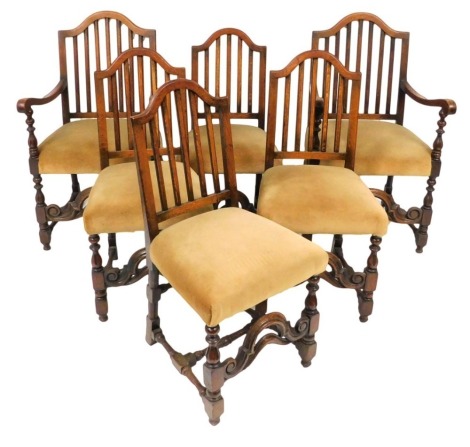 A set of six early 20thC Carolean/Georgian style oak dining chairs, with yellow dralon overstuffed seats, raised on turned legs united by a H frame stretcher, comprising a pair of carvers and four single chairs.