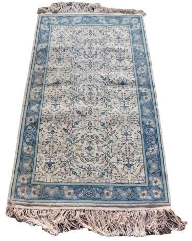 A Tunisian cream ground rug, the central field decorated with floral motifs within a repeating floral border, 158cm x 92cm.