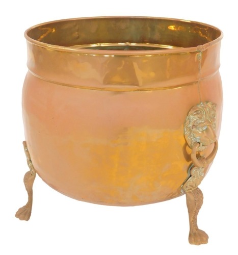 A Victorian copper and brass log bucket, of globular form with raised rim, with two lion's head ring handles, raised on three lion's paw feet, 45cm high, 46cm diameter.