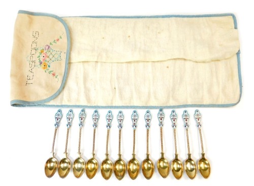 A set of twelve early 20thC Russian silver gilt and enamel coffee spoons, each with a shaped top, on twist stem with cream and blue floral enamel back, white metal stamped 88 fineness, 6oz.