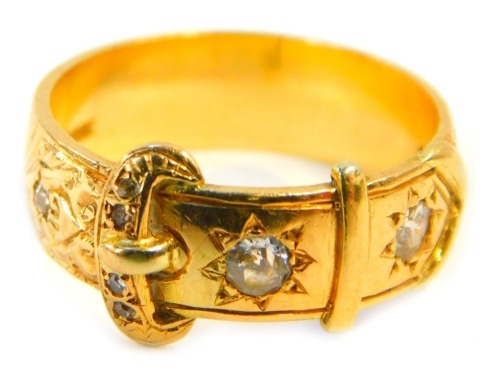 A Victorian buckle ring, set with two large old cut diamonds and five small old cut diamonds, each in buckle form with a scroll decoration, yellow metal stamped 18ct, ring size Q, 7g all in.