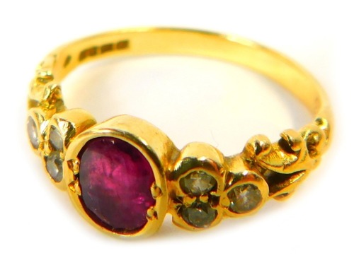 An 18ct gold ruby and diamond dress ring, the central oval ruby in a rub over setting, with three tiny diamond set shoulders and V splayed scrolled supports, ring size N, 3.6g all in.