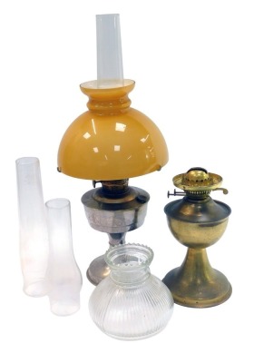 A 20thC oil lamp, with yellow glass shade above a chrome base, with chimney, 60cm high, together with a further brass oil lamp base, two glass chimneys and a moulded glass shade.