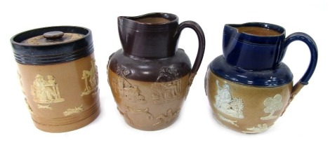 A group of Royal Doulton two tone stoneware, with sprig moulded decoration, comprising jar and cover, 15cm high (AF), and two jugs, one with a blue glazed section to top of jug and handle, impressed marks, 17cm high, and another.