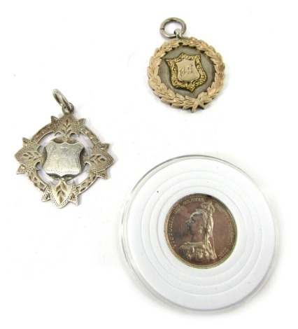 A Queen Victoria silver shilling, dated 1887, together with two silver fobs, one with gilt decoration engraved verso HB & DCL CV 1911.