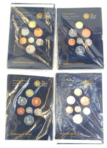 Four Royal Mint United Kingdom brilliant uncirculated coin collections, two for the Emblems of Britain and two for the Royal Shield of Arms, in plastic packaging.