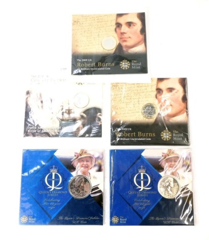 A group of Royal Mint commemorative coinage, comprising a 2009 Charles Darwin two pound brilliant uncirculated coin, two 2009 Robert Burns two pound brilliant uncirculated coins, and two Queen Elizabeth II Diamond Jubilee coins, in plastic packaging.