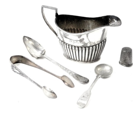 A George V silver cream jug, with reeded design and inscribed G&JN April 23rd 1914, Birmingham 1914, a silver thimble, Victorian silver teaspoon, pair of silver George V sugar tongs, 3.23oz, and an Argentina silver toddy spoon. (5)