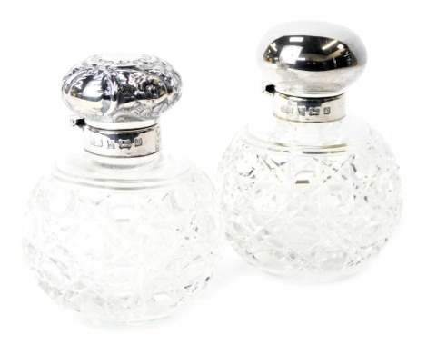 Two silver topped and cut glass dressing table jars, the jars with floral scroll design, Birmingham 1971, the other of plain design, 10cm high. (2)