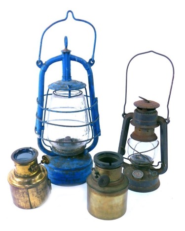 Two early 20thC Tilley lamps, comprising one in a painted blue steel carry case, 38cm high and another 25cm high and two brass magic lantern lens casing. (4)