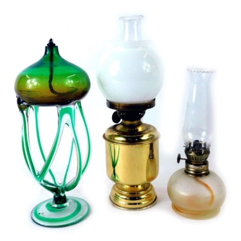 Three glass oil lamps, comprising a green twist stem lamp, brass cased lamp and another, the largest 29cm high.