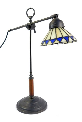 A Tiffany style table lamp, the adjustable arm with a cream and blue diamond Tiffany style shade, on a stepped circular foot base, 43cm high.