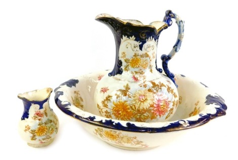 A late 19thC pottery wash jug and bowl set, toothbrush holder, each decorated with flowers picked out in gilt. (3)