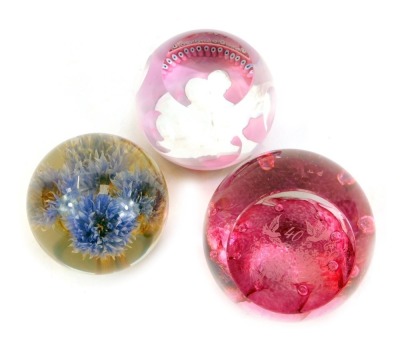 Three glass paperweights, comprising a Caithness Prince and Princess of Wales limited edition number 10/500 pink glass paperweight, a Caithness Celebration weight, and a Hafod Grange paperweight 1995 thistle weight. (3)