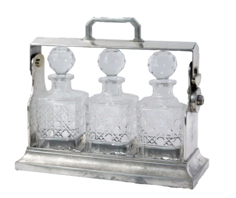 A 20thC silver plated Tantalus, with three cut glass decanters and stoppers, the stand is stamped silver on copper plate, Made in England, 30cm high, 34cm wide, 14cm deep. (AF)