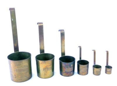 A set of six brass barrel measuring cups, each with arched hook handle, going from 1cl to half a litre, 26.5cm high.