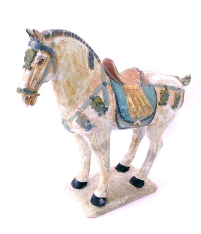 A mid to late 20thC plaster model of a Tang horse, overpainted, with blue and brown saddle, on a rectangular base, 46cm high, 47cm wide.