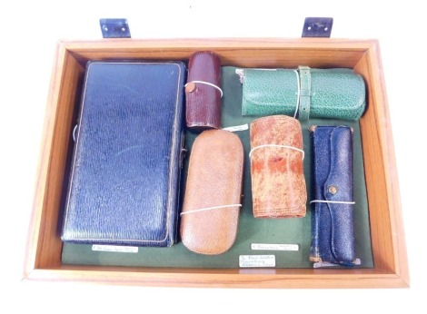 A group of leather travel sewing cases, comprising a brown leather case of cylindrical form containing two reels and a plated thimble, and a case containing mother of pearl handled button hook, file, various reels, etc.