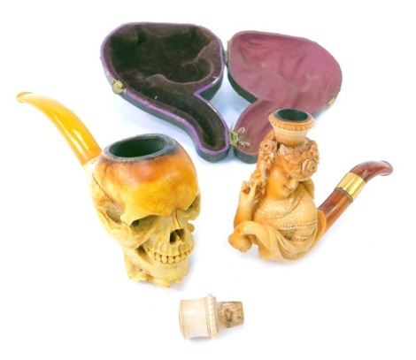 A meerschaum pipe, modelled as a hand holding skull, with simulated amber cheroot, 15cm long, together with a further meerschaum pipe modelled as a lady wearing Edwardian dress, 10cm long, cased.