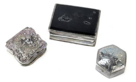 Three white metal pill boxes, comprising a rectangular pill box, with black agate top, lacking transfer design, a hexagonal pill box, and an arched shaped pill box, with cherub and scroll decoration, each white petal stamped 925, 1.32oz. (3)