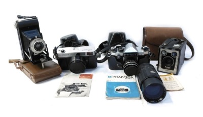 A group of cameras, comprising a Kodak folding camera F6.3, a Kodak Brownie model D camera, in canvas case, a Canon Canonette 35mm camera, in black leather case, a Praktica Super TL camera, in black leather case, and an Optomax telephoto lens.