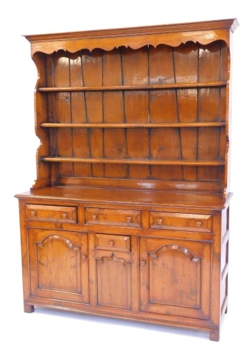 An oak Welsh dresser in 18thC style, the top with a moulded edge with three shelves, the base with three moulded drawers with turned handles, above a central small drawer flanked by two panelled cupboards, on stiles, 200cm high, 152cm wide, 51cm deep.