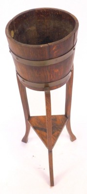 An early 20thC oak plant stand, the circular top with cooper banding, on square outswept legs united by an under tier, 90cm high. - 2