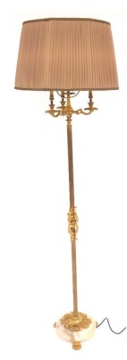 A 20thC brass three branch standard lamp, with a reeded cylindrical column embellished with ornate scroll motifs, on a circular marble base, on three brass paw feet, with shade, 167cm high overall.