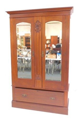 An Art Nouveau walnut wardrobe, the top with a moulded edge above two mirrored doors, enclosing brass rails to each side, central panel decorated with Art Nouveau floral motif, the base with a drawer, on plinth, approx 208cm high, 128cm wide, 47cm deep.