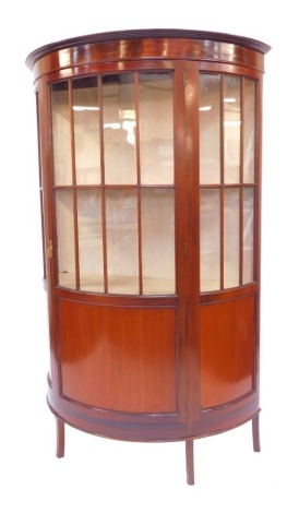 An Edwardian mahogany bow front display cabinet, the top with a moulded edge above a panelled half glass door, and two further glass sections to each side, with drawers to base, on square legs, 162cm high, 105cm wide, 46cm deep.