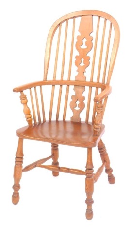 An elm spindle back Windsor chair, with pierced splat, solid seat, on turned legs united by a H shaped stretcher.