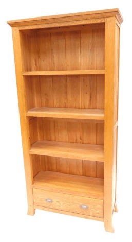 A modern oak open bookcase, the top with a moulded cornice above four shelves, with drawer to base, on out swept feet, 184cm high, 93cm wide, 33cm deep.