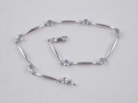 A stone set bracelet with oval aquamarines and bar links in white metal stamped 375