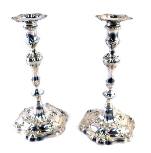 A pair of George III silver candlesticks, each with shell capped hexagonal scrolling base, on a reeded stem, London 1767 by Ebenezer Coker, 45.78oz, 27cm high. (2)