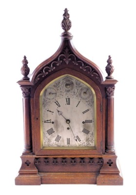 A Victorian gothic bracket clock, the oak case decorated with scrolls, pillars, and leaf carved finials, the arched dial with slow/fast, charm/silent, full chime/Westminster chime subsidiary dials, surrounding a Roman numeric dial with engraved spandrels,