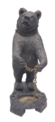 A Black Forest style composition umbrella stand, modelled in the form of a standing bear holding a chain, the shaped carved wood base with recess for drip pan, 92cm high.