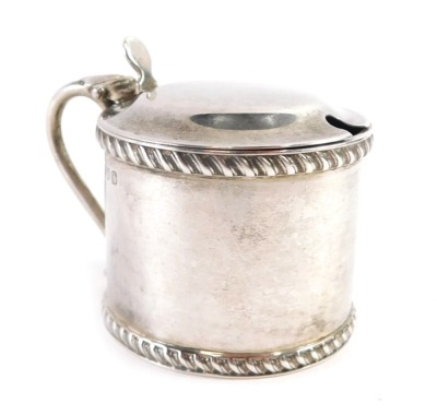 An Edward VII silver drum shaped mustard, with moulded thumb piece, the body of plain design with a reeded border, with blue glass liner, Birmingham 1901, 2oz.