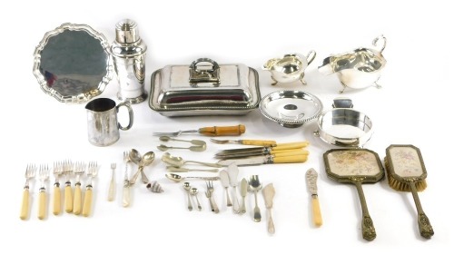 A group of assorted silver plated wares, comprising two silver plated sauce boats, entree dish, cocktail shaker, bone handled cutlery, dressing table, mirror and brush, etc. (a quantity)