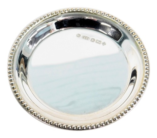 A Queen Elizabeth II silver pin dish, with a beaded border, hallmark to commemorate The Millennium, 0.83oz, 8.5cm diameter.