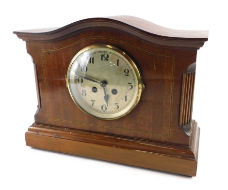 An Edwardian mahogany and chequer banded mantel clock, with a shaped top, silvered dial, on a plinth, 27cm high.